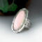 large oval pink conch stone bezel set accented with stamped cutout wire on tapered wide band